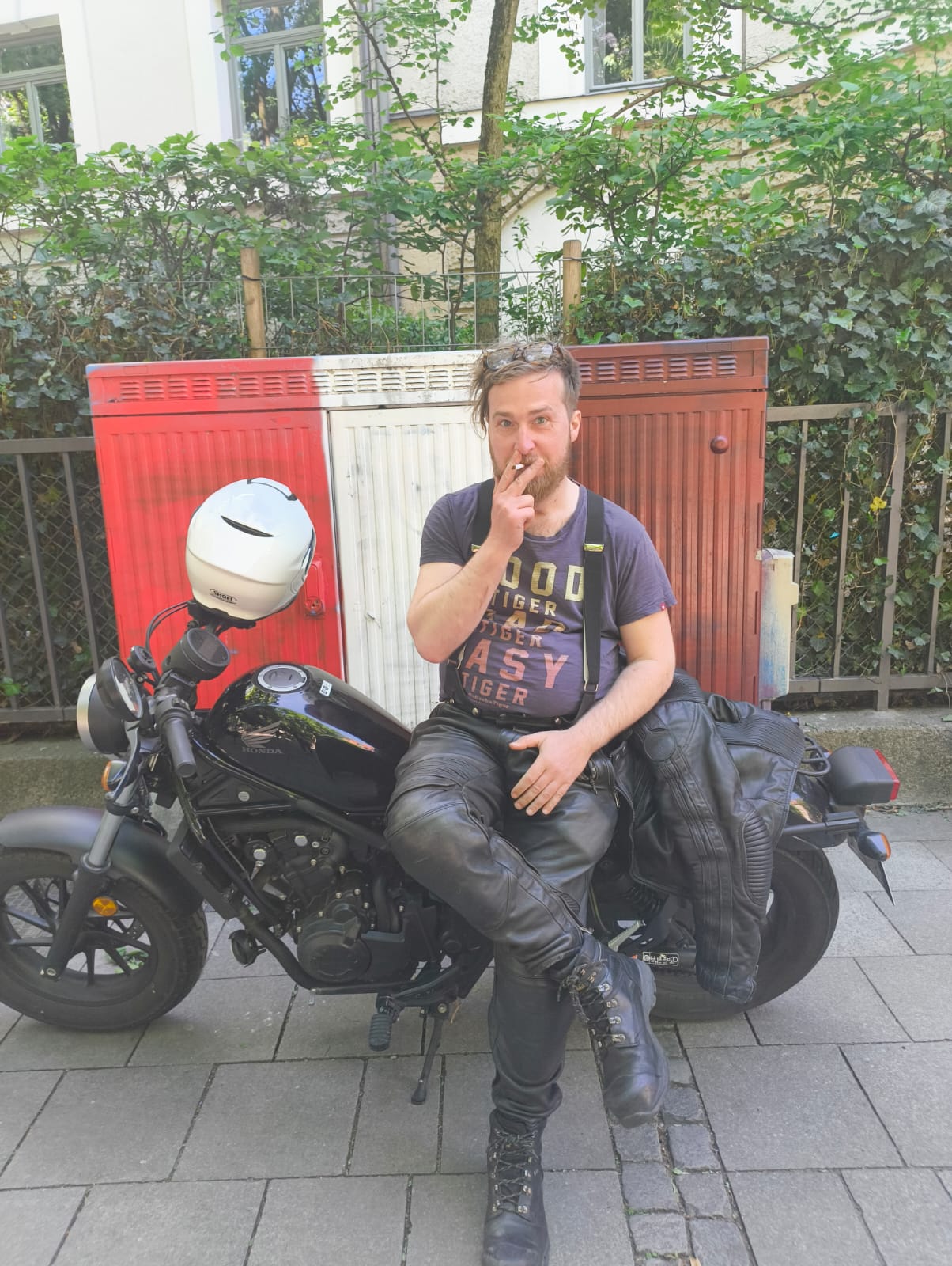 Ich in schwarzer Ledermontur seitlich sitzend auf meinem Motorrad. Auf meinem T-Shirt steht "Good tiger, bad tiger, easy tiger"