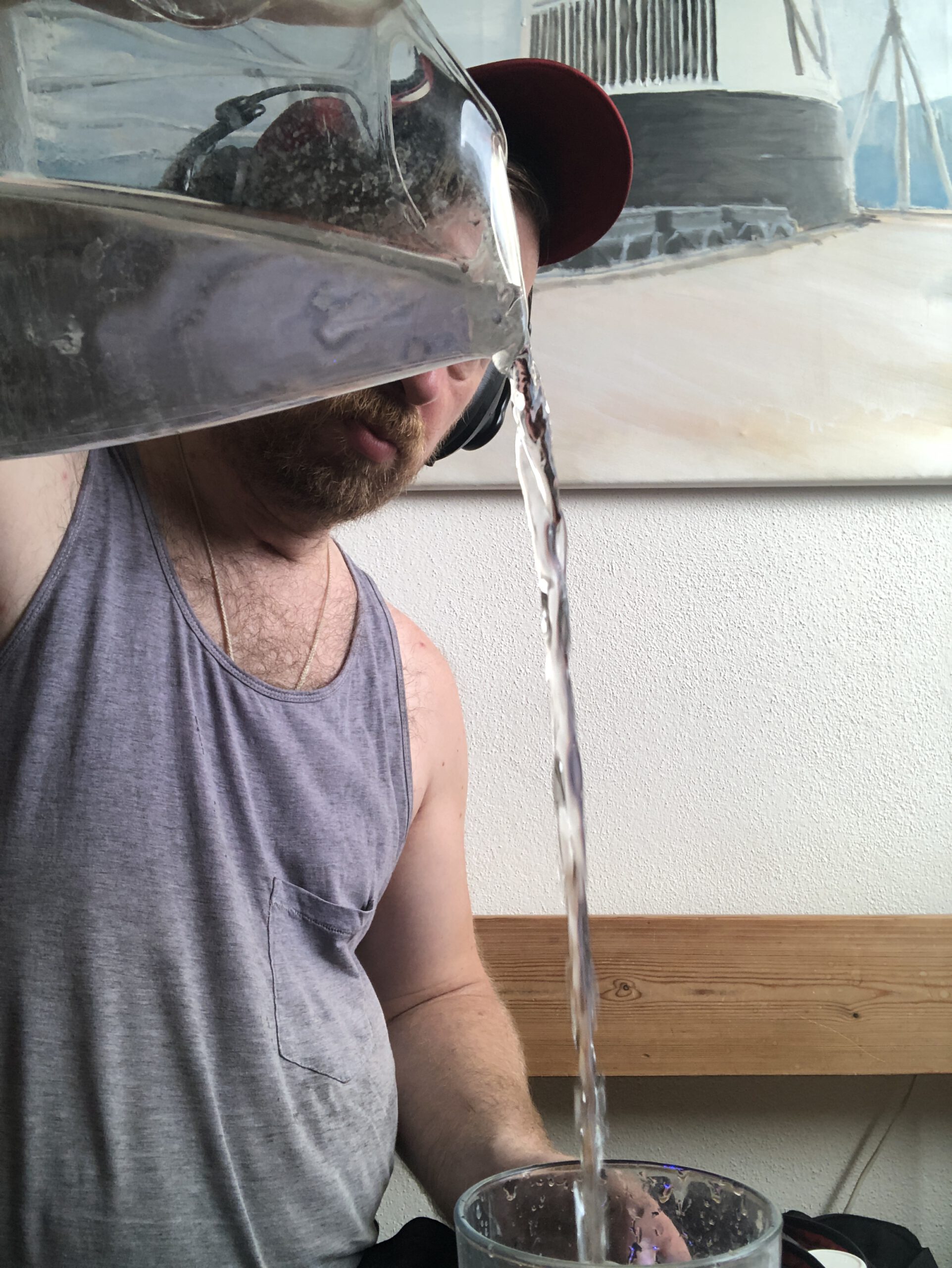 Ich auf der Küchenbank, während ich in hohem Bogen aus einer Glaskaraffe Wasser in ein Glas gieße